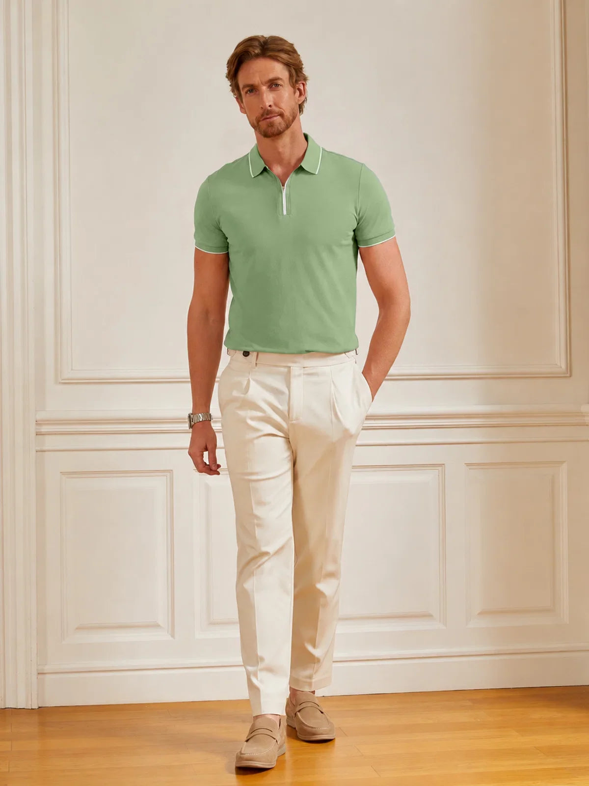 Man wearing a light green performance golf polo and white trousers.