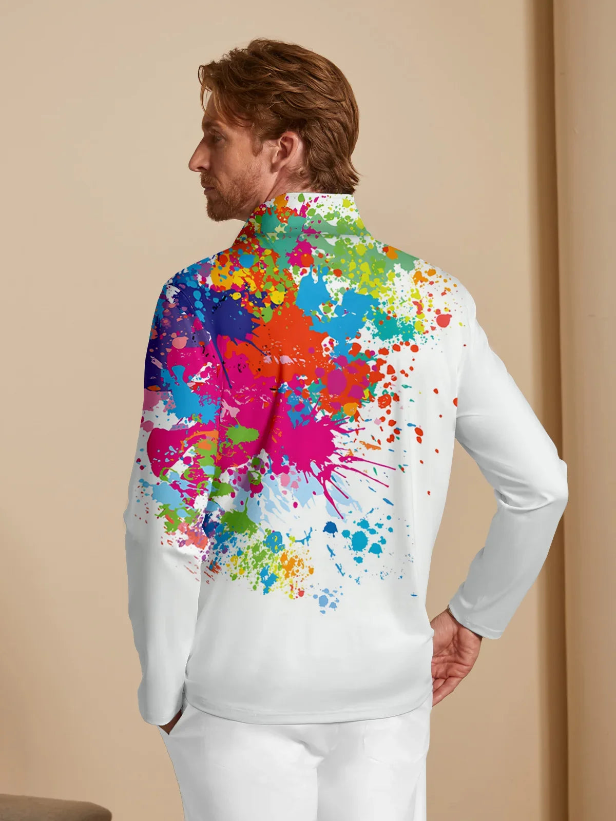 Man wearing a white performance golf quarter-zip with a colorful paint splatter print.