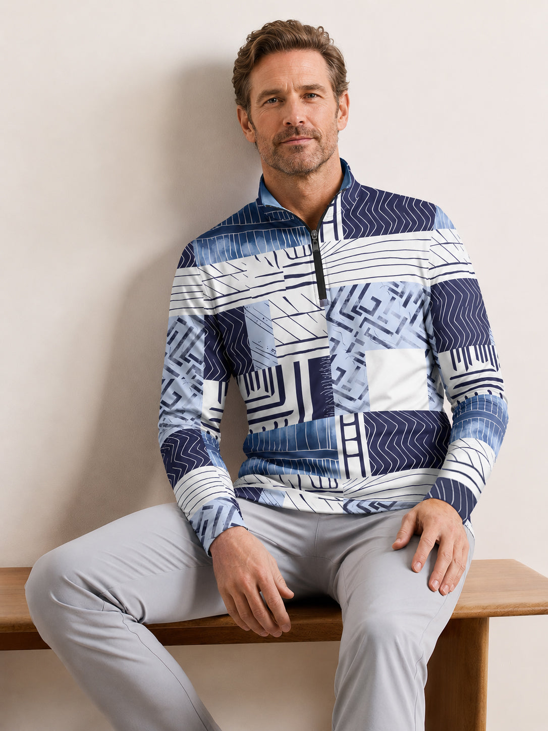 Man wearing a blue and white geometric print quarter-zip golf shirt and grey pants.