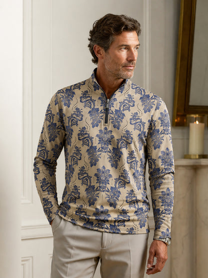 Man wearing a blue and beige damask print performance quarter-zip golf shirt and beige pants.
