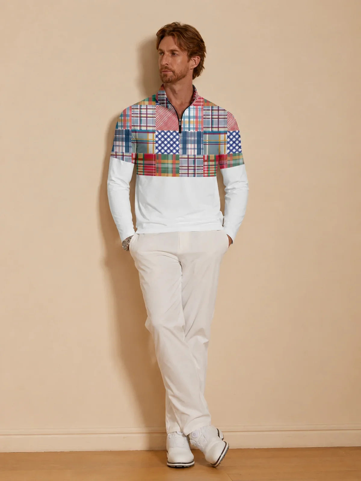 Man wearing a colorful patchwork print quarter-zip golf shirt and white golf pants.
