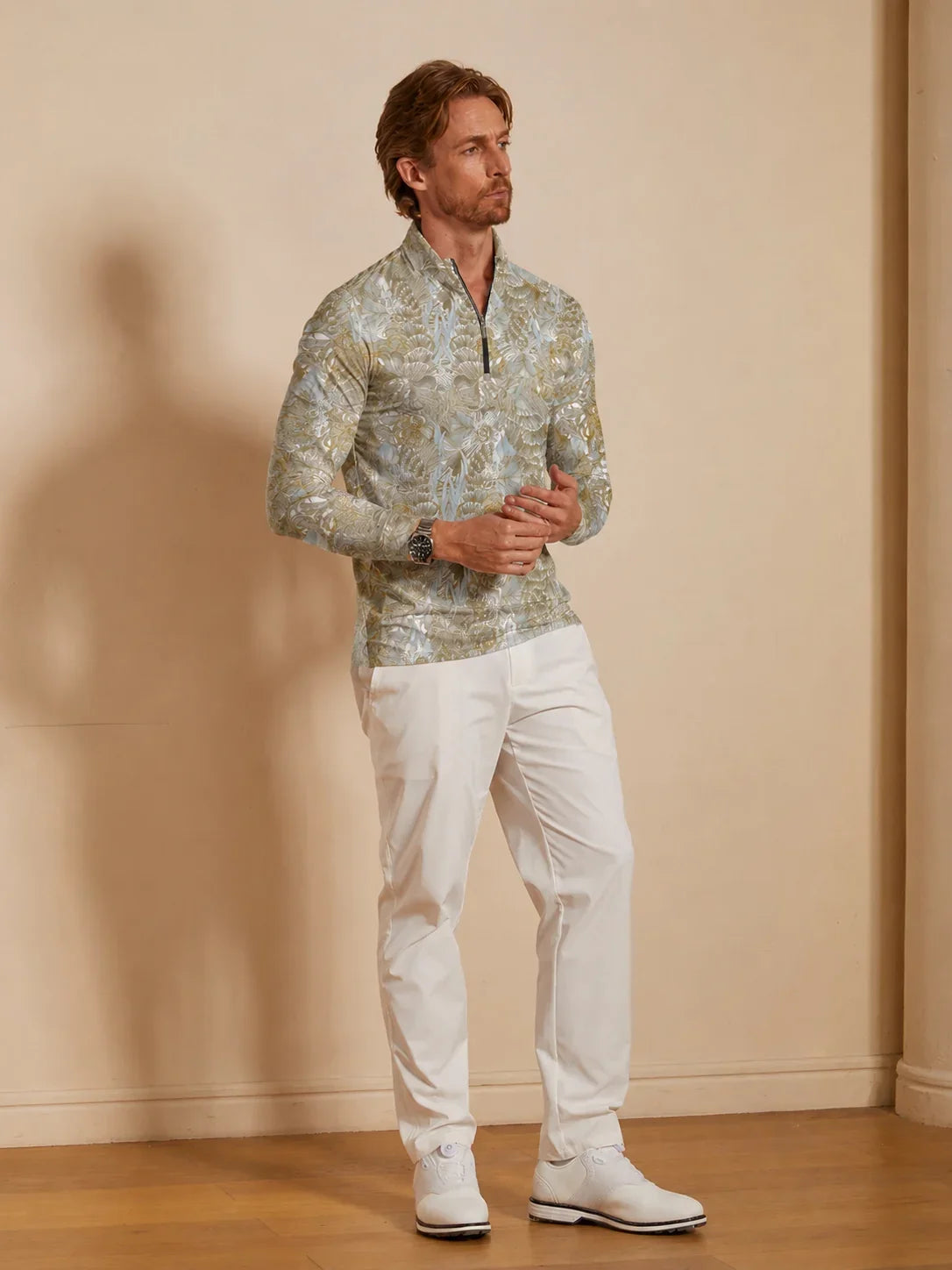 Man wearing a patterned quarter-zip performance golf shirt and white golf pants.