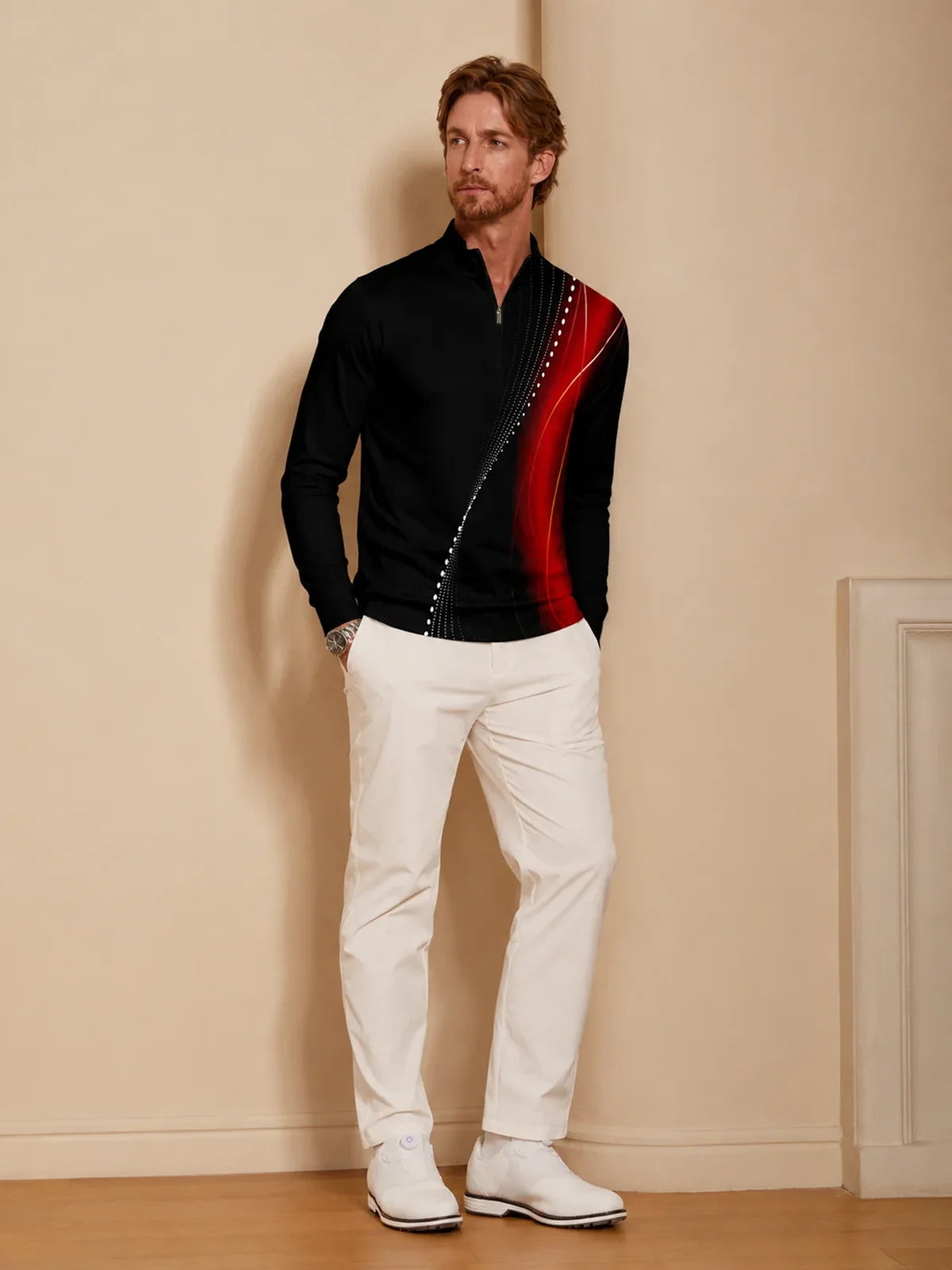 Man wearing a black performance quarter-zip golf pullover with red accents and white pants.