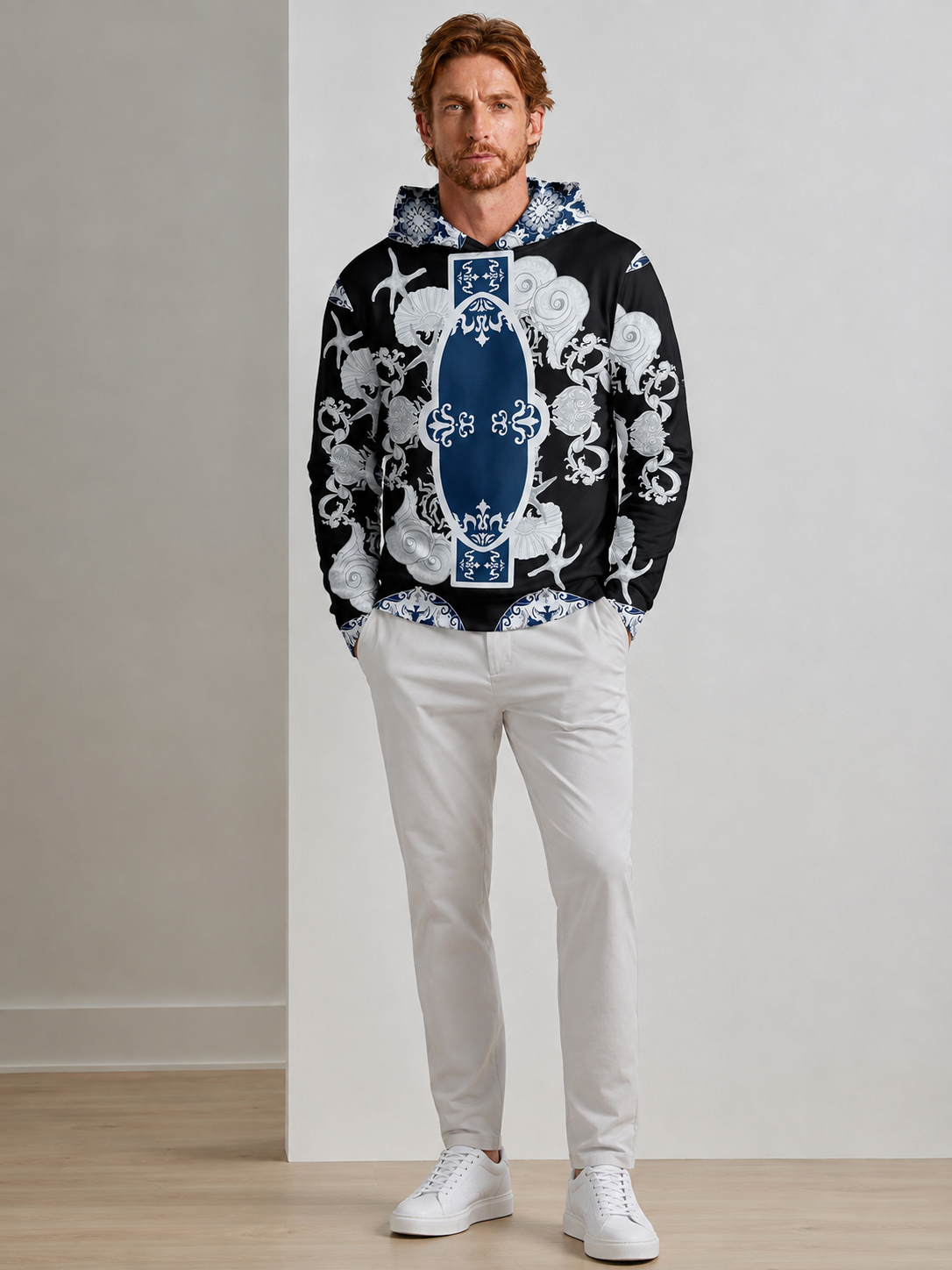 Man wearing a black and white nautical print hoodie and white trousers.
