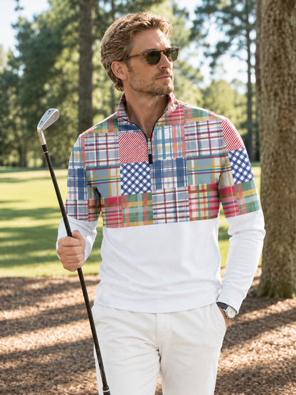Man wearing a colorful plaid performance golf quarter-zip pullover and white pants.